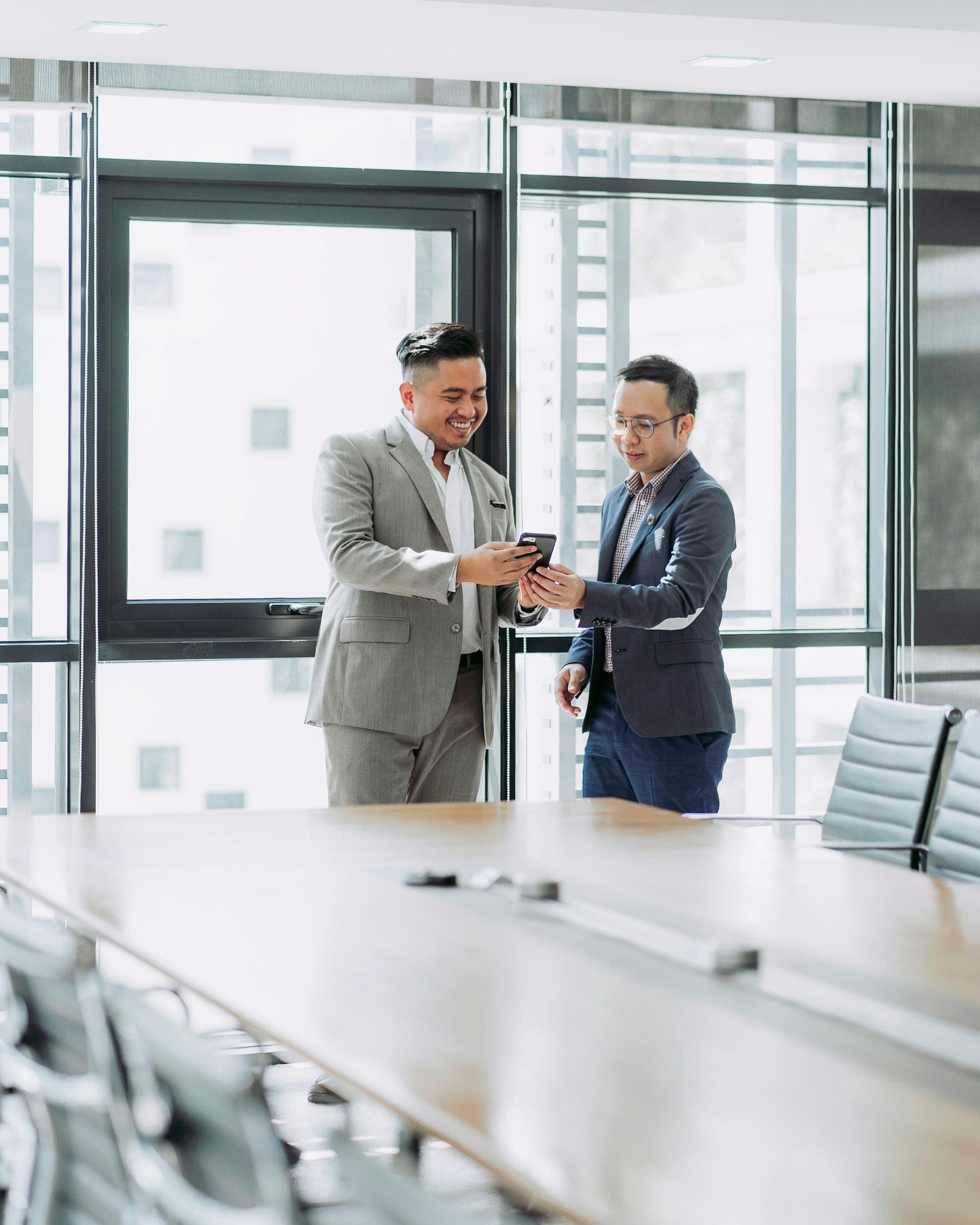 Two advisors reviewing a transaction on a phone in a glass office