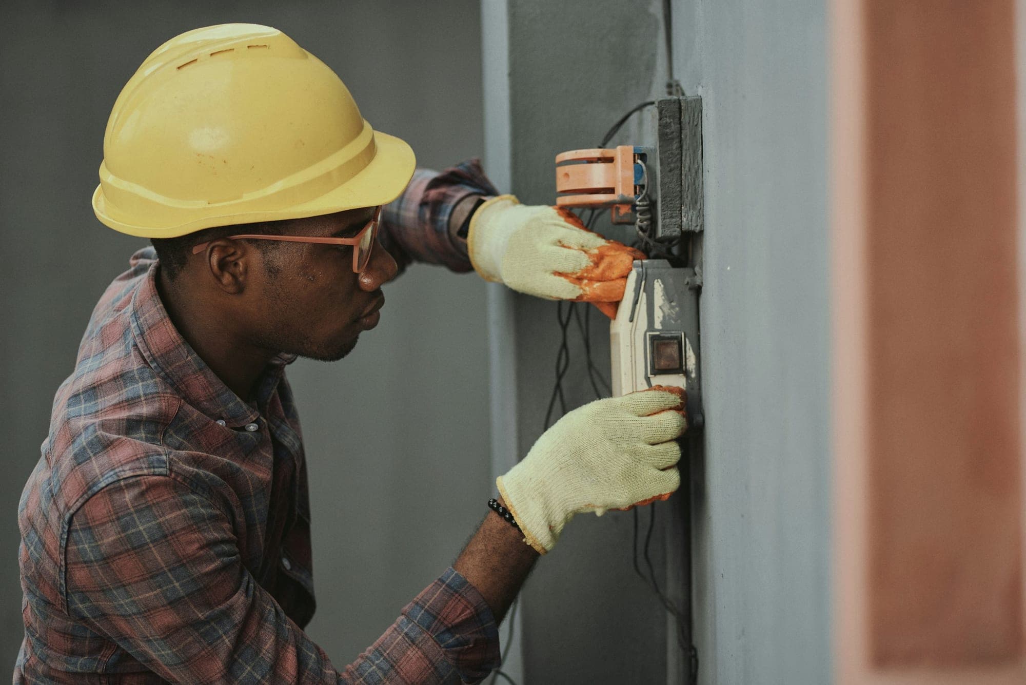 Technician in a hard hat servicing a building utility panel